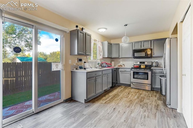 kitchen featuring gray cabinets, a wealth of natural light, pendant lighting, and black appliances