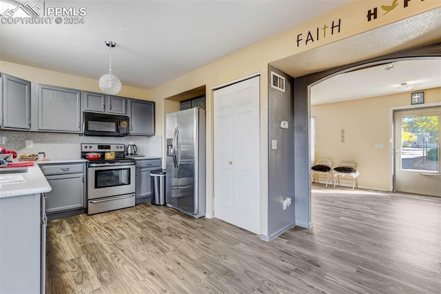 kitchen featuring appliances with stainless steel finishes, light hardwood / wood-style floors, pendant lighting, and gray cabinetry