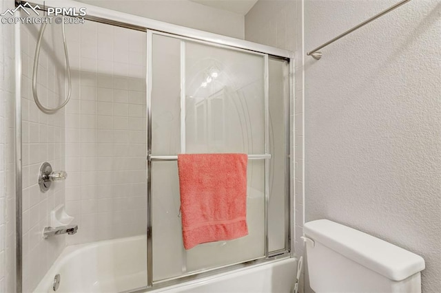 bathroom featuring toilet and bath / shower combo with glass door