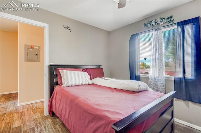 bedroom featuring electric panel, ceiling fan, and hardwood / wood-style floors