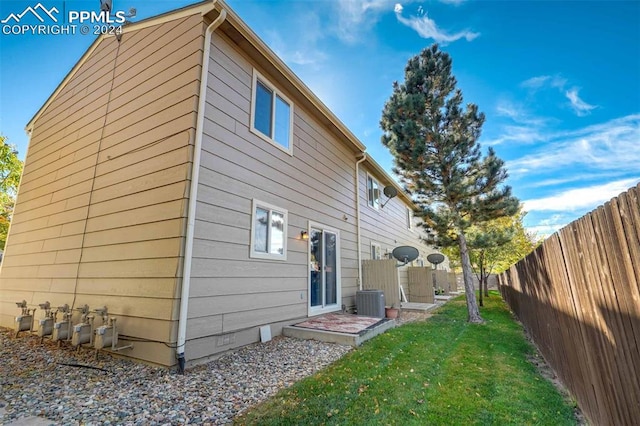 rear view of property with a lawn and central AC unit