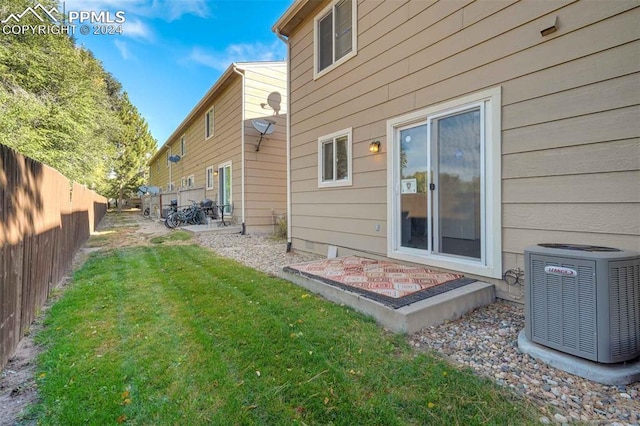 rear view of house featuring a patio, a yard, and central AC