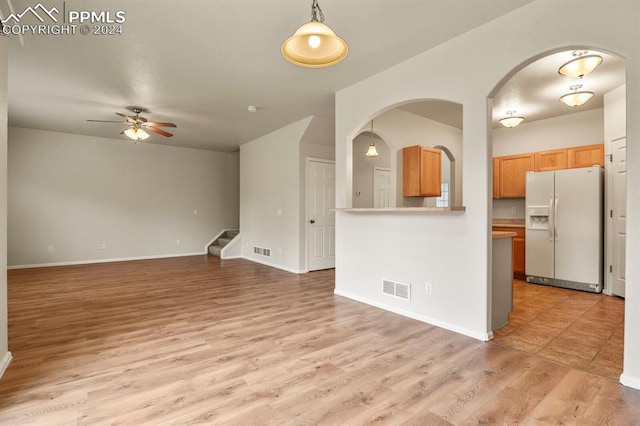 kitchen featuring white refrigerator with ice dispenser, pendant lighting, light hardwood / wood-style flooring, and ceiling fan