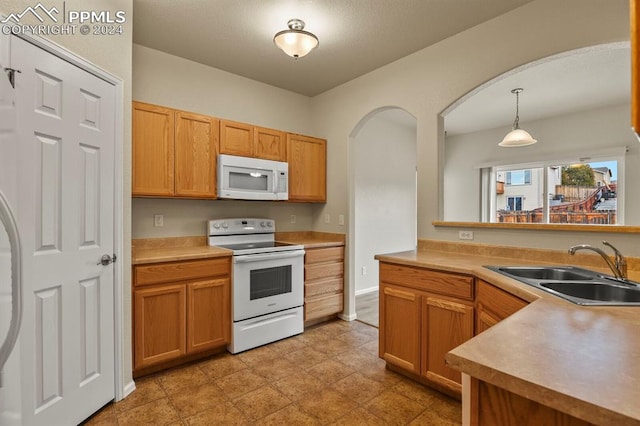 kitchen with pendant lighting, white appliances, and sink