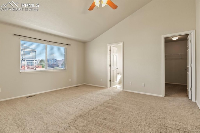 interior space featuring connected bathroom, ceiling fan, light colored carpet, a walk in closet, and a closet