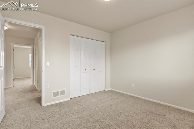 unfurnished bedroom with light carpet and a closet