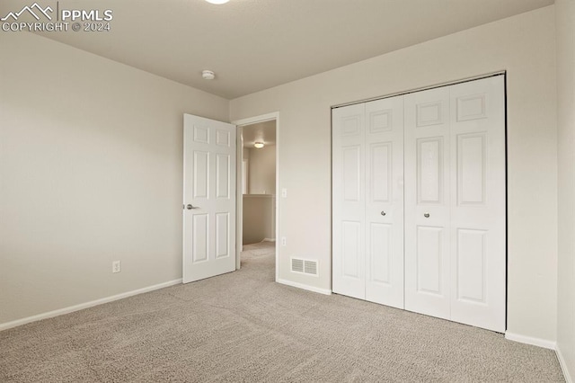 unfurnished bedroom featuring light carpet and a closet