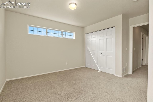 unfurnished bedroom featuring light carpet and a closet