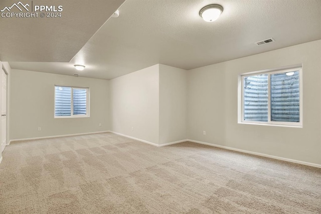 carpeted empty room featuring a textured ceiling