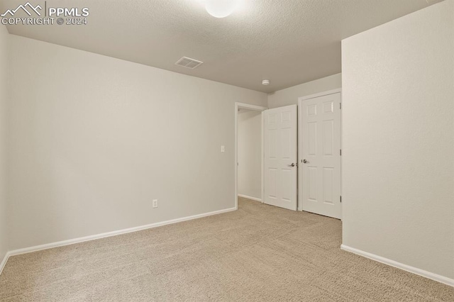 spare room with light colored carpet and a textured ceiling