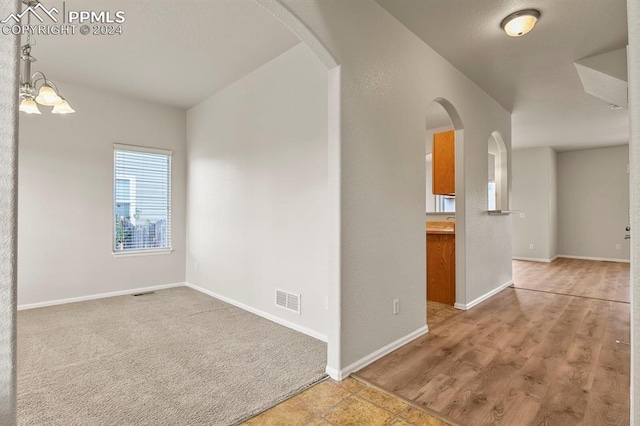 spare room with a chandelier and light wood-type flooring