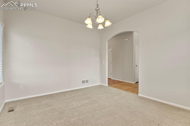 spare room with light carpet and a chandelier