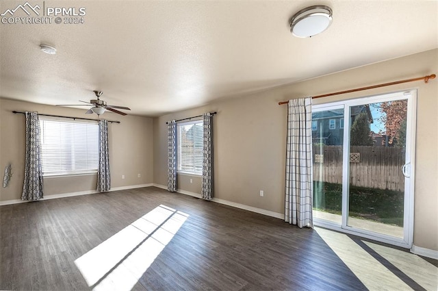 empty room with dark hardwood / wood-style floors, a healthy amount of sunlight, and a textured ceiling