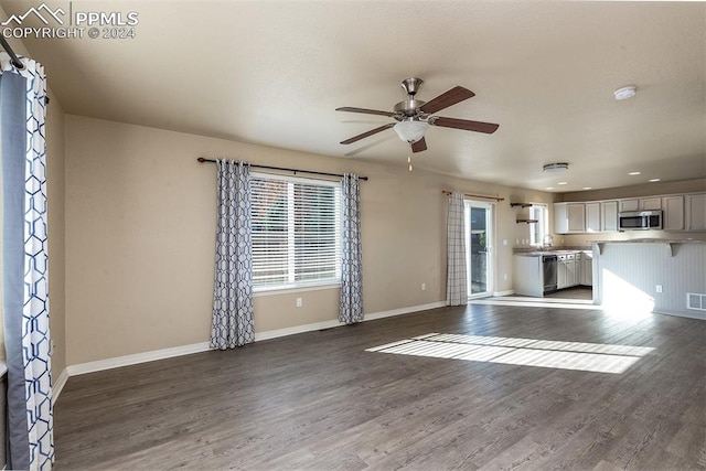 unfurnished living room featuring ceiling fan, dark hardwood / wood-style floors, and sink