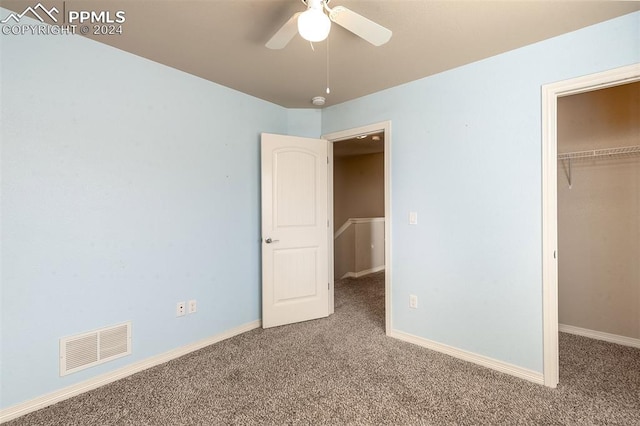 unfurnished bedroom featuring ceiling fan, a closet, a spacious closet, and carpet