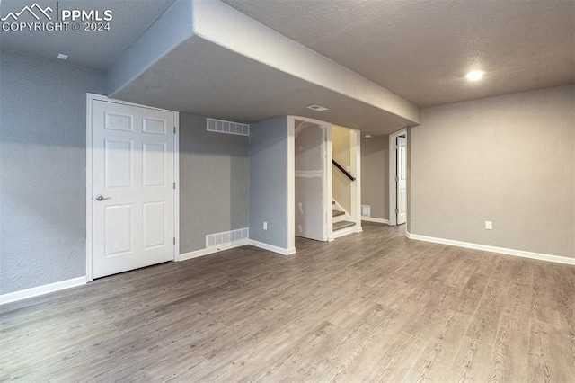 basement featuring wood-type flooring and a textured ceiling