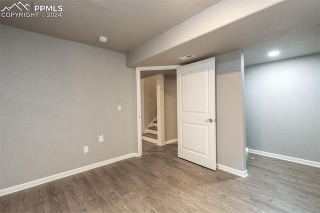 basement featuring wood-type flooring and a textured ceiling