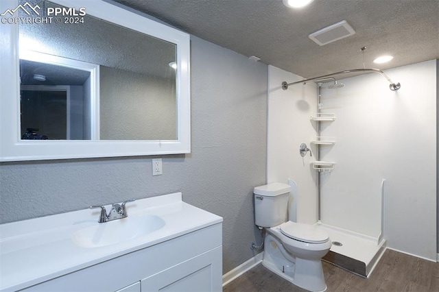 bathroom featuring wood-type flooring, walk in shower, vanity, a textured ceiling, and toilet