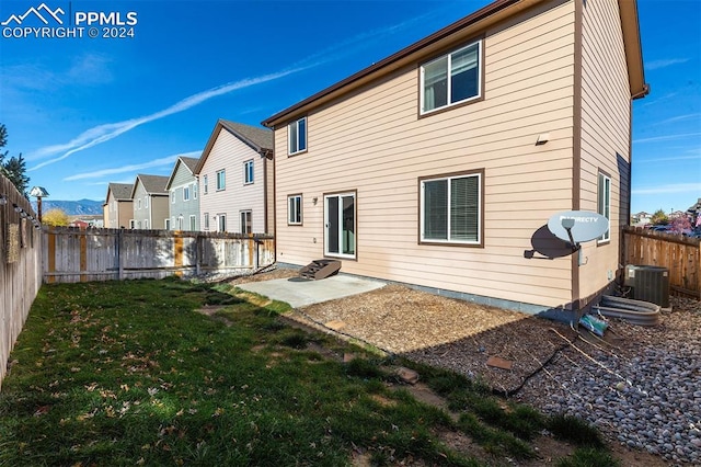 back of property with cooling unit, a lawn, and a patio area