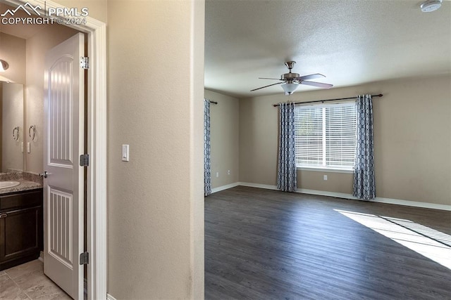 empty room featuring a textured ceiling, light wood-type flooring, and ceiling fan