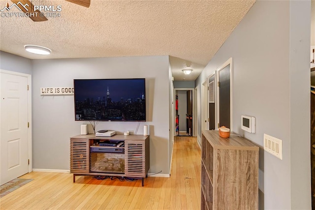 living room featuring hardwood / wood-style floors, a textured ceiling, and ceiling fan