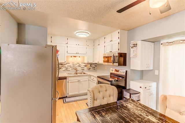 kitchen featuring backsplash, ceiling fan, light hardwood / wood-style floors, stainless steel appliances, and white cabinets