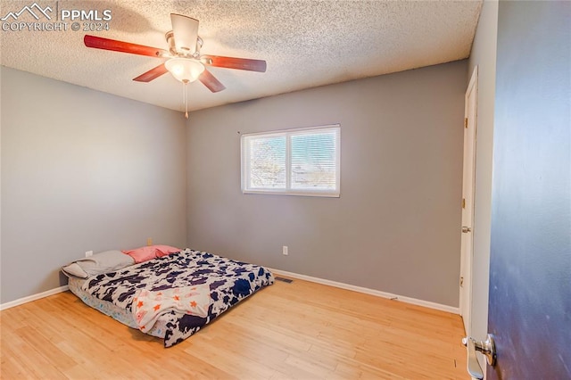 bedroom featuring ceiling fan, wood-type flooring, and a textured ceiling