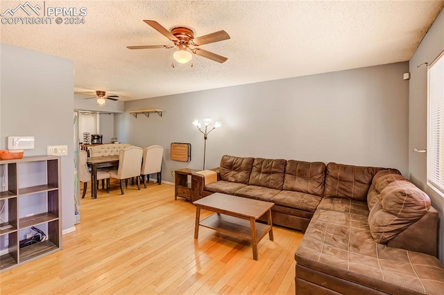 living room featuring a textured ceiling, light wood-type flooring, and ceiling fan