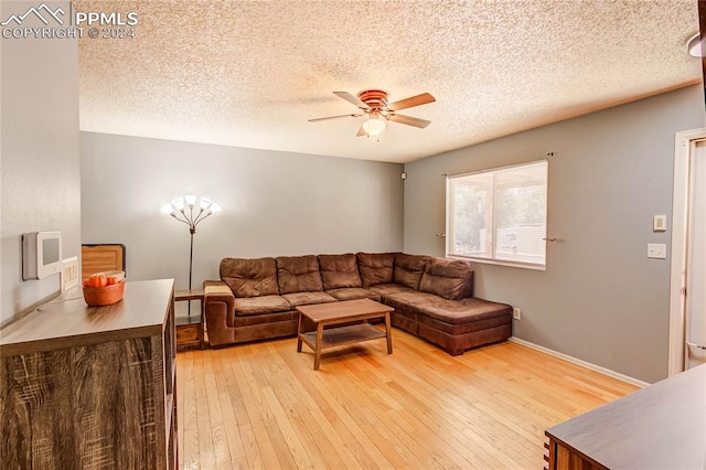 living room featuring light hardwood / wood-style flooring, a textured ceiling, and ceiling fan