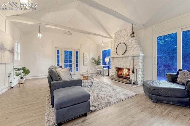 living room with hardwood / wood-style floors, vaulted ceiling with beams, and a stone fireplace