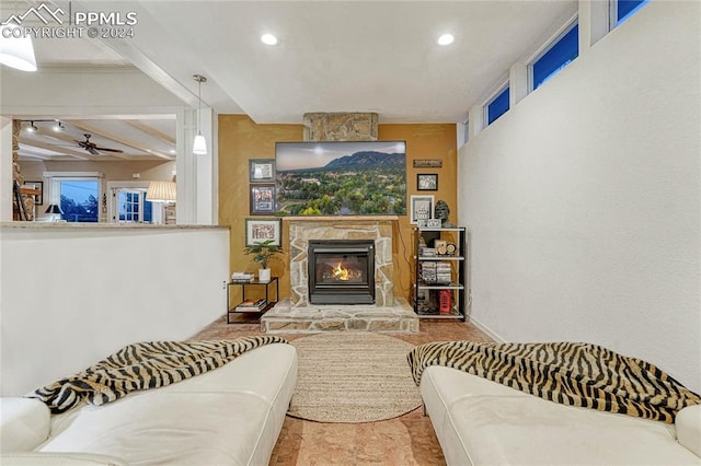 living room with ceiling fan, a fireplace, and beamed ceiling