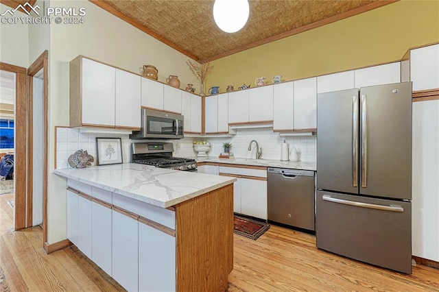 kitchen featuring decorative backsplash, light wood-type flooring, stainless steel appliances, and white cabinetry