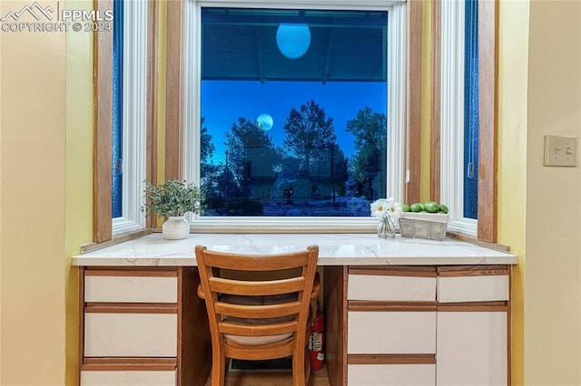 bar with white cabinetry and built in desk