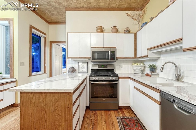 kitchen with kitchen peninsula, appliances with stainless steel finishes, light hardwood / wood-style floors, and white cabinets