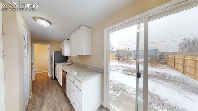 kitchen featuring light stone countertops, sink, hardwood / wood-style floors, stainless steel appliances, and white cabinets