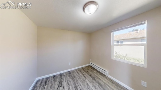 spare room with a baseboard heating unit and hardwood / wood-style floors