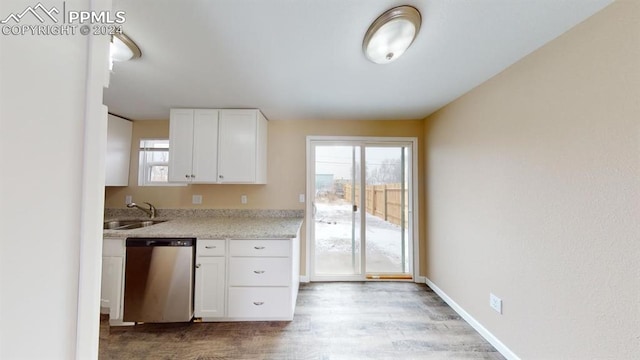 kitchen with light stone countertops, sink, light wood-type flooring, white cabinetry, and stainless steel dishwasher