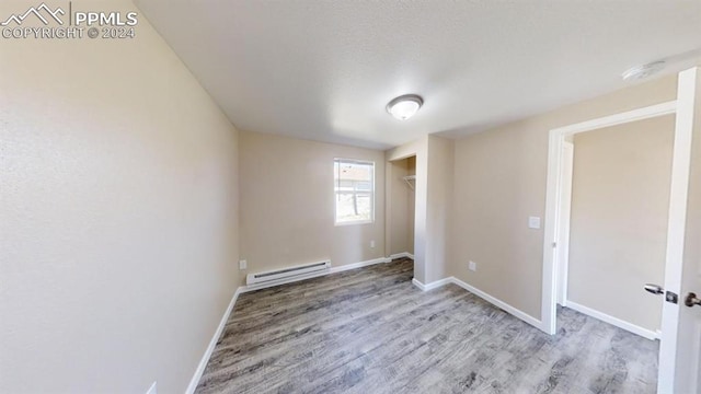 spare room with a baseboard heating unit and light hardwood / wood-style floors