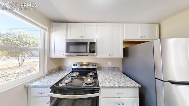 kitchen with white cabinetry, light stone countertops, and appliances with stainless steel finishes