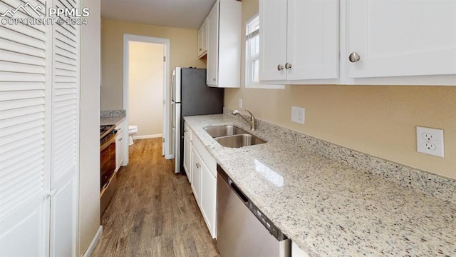 kitchen with hardwood / wood-style floors, sink, light stone countertops, white cabinetry, and appliances with stainless steel finishes