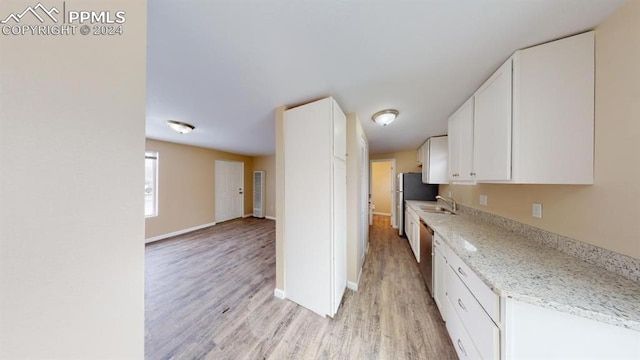 kitchen with light stone countertops, sink, white cabinetry, light hardwood / wood-style floors, and stainless steel appliances