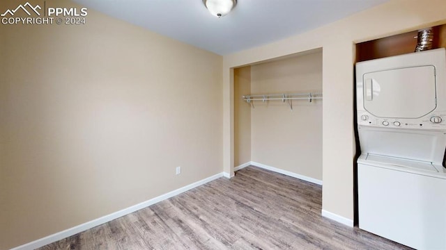 laundry area featuring stacked washer / dryer and hardwood / wood-style floors