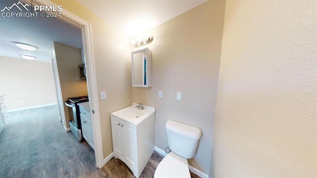 bathroom with toilet, hardwood / wood-style floors, and vanity