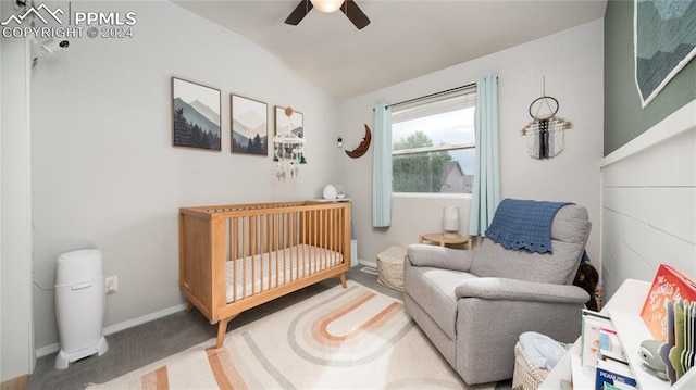 bedroom with carpet, a crib, vaulted ceiling, and ceiling fan