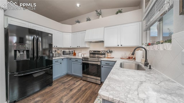 kitchen with appliances with stainless steel finishes, sink, lofted ceiling, custom exhaust hood, and white cabinets