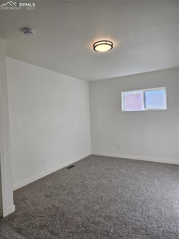 carpeted spare room with a textured ceiling