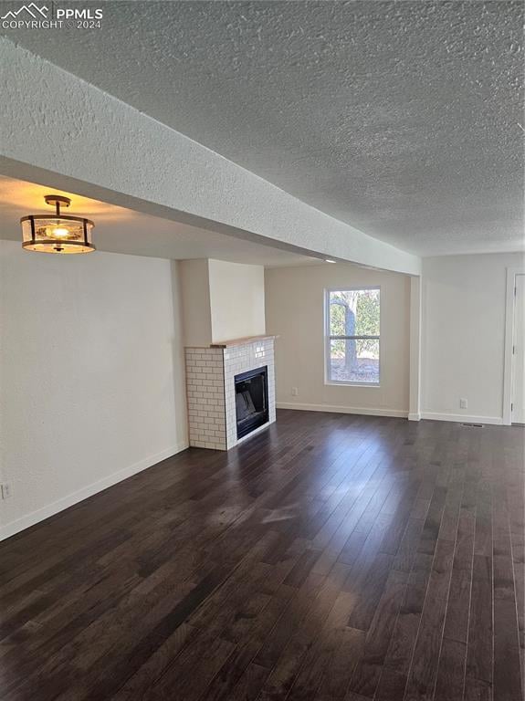 unfurnished living room featuring dark hardwood / wood-style flooring and a textured ceiling