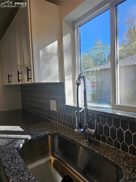 kitchen with dark stone counters, tasteful backsplash, and white cabinets