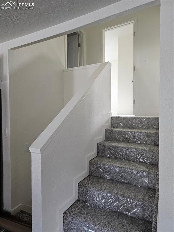 stairs featuring a textured ceiling