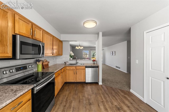 kitchen featuring tasteful backsplash, appliances with stainless steel finishes, a notable chandelier, sink, and dark wood-type flooring